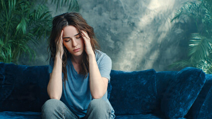 Depressed Woman Sitting on Couch with Headache