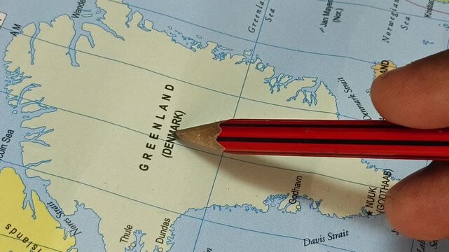 Closeup of pencil tip touching greenland autonomous territory land of denmark location marked on a map. Geopolitics and travel tourism creative concept.
