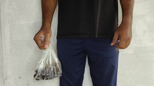 Indian person hand holding fruits inside single use disposable plastic carry bag cover leads to microplastic particle contamination inside food. Grocery packaging using cheap packing wrappers concept.