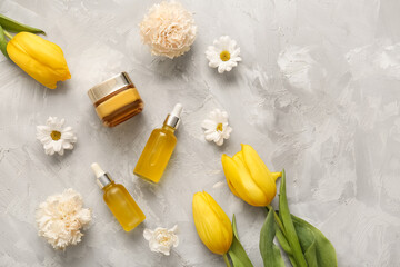 Different cosmetics and beautiful flowers on grey background