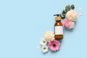 Cosmetics and beautiful flowers on blue background