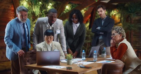 Multicultural business team reacts with shock and disappointment to bad news during meeting as Japanese businesswoman reviews negative results on laptop in modern office. - Powered by Adobe