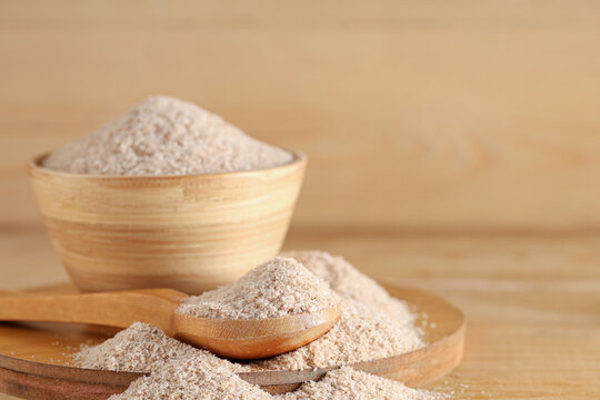 Bowl and spoon with psyllium husk powder on wooden background
