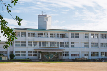 夏の青空と日本の田舎にある白い校舎の風景（アニメ風背景素材・コピースペース）

