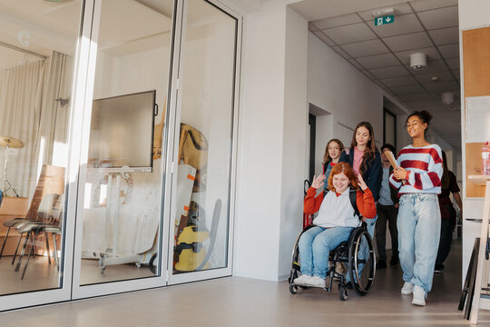 Teen students in school hallway, girl in wheelchair.