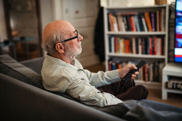 Elderly man watching television alone at home.