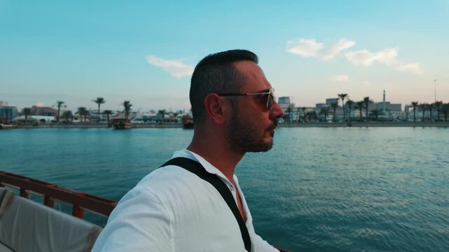 A tourist man enjoy boat tour with dhow cruise ships in Doha, Qatar