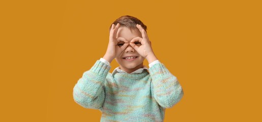 Funny little boy showing OK on yellow background