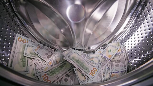hand is throwing the United States Dollar banknotes in washing machine drum, money laundering and fraud concept.