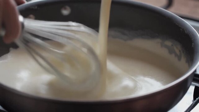 Creamy sauce being whisked in a pan on stovetop