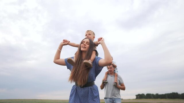 A woman and two children in a field. Family of children walking in the park. Mother and dad walking their children in nature. A lifestyle female and two kids in a meadow.