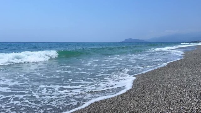 The Mediterranean Sea and the foaming waves in Mahmutlar during the day in sunny weather. Alanya. The waves crash against the shore. The turquoise water on the beach in Turkey.The coastline is wide.4К