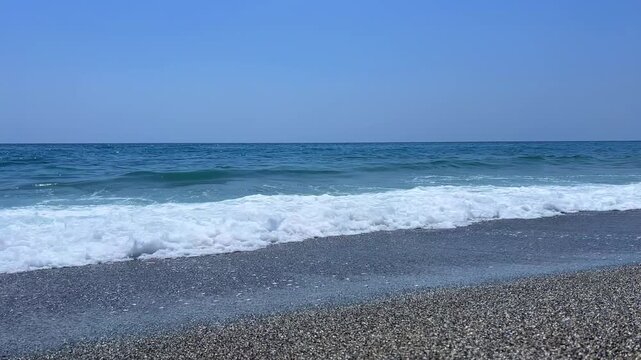 The Mediterranean Sea and the foaming waves in Mahmutlar during the day in sunny weather. Alanya. The waves crash against the shore. The turquoise water on the beach in Turkey.The coastline is wide.4К
