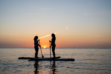Paddle boarders moving calmly across the water at sunset, mindful outdoor moment with relaxation