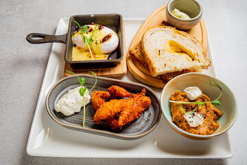 Delightful breakfast features poached eggs, crispy chicken, fresh bread, and creamy dips