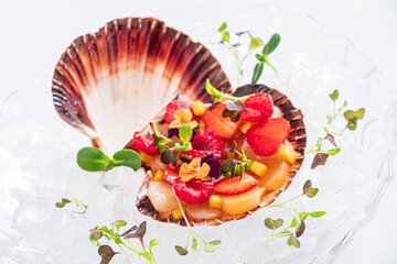 A scallop shell holds a vibrant blend of fruits, herbs, and flowers in a stunning dish