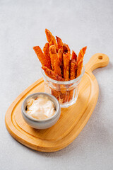 Delicious sweet potato fries sit in a clear jar alongside a small bowl of creamy dip