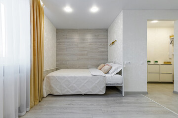 Modern studio apartment bedroom area with wooden accent wall and bed