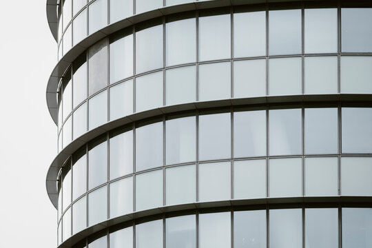 Abstract modern corporate architecture building facade of glass windows in a circular tiered form with smooth geometry pattern and panoramic feel