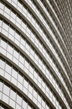 Abstract modern corporate architecture building facade of glass windows with sweeping curved bands creating futuristic geometry pattern on tower detail
