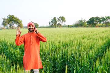 indian farmer talking on mobile phone at wheat agriculture field