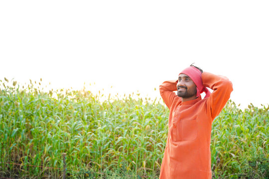 Happy indian farmer at green sorghum, millet or jowar agriculture field