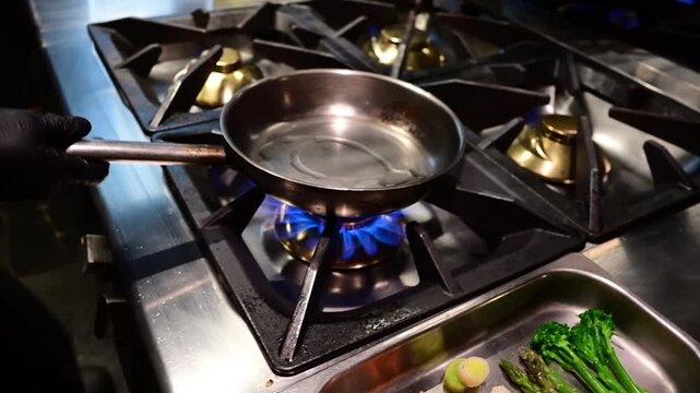 Professional chef flambeing and tossing fresh vegetables in a pan