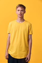 Fototapeta premium Young man wearing a yellow T shirt in a bright studio, casual fashion and relaxed pose, clean background, ideal for lifestyle or apparel showcase