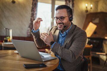 Fototapeta premium Man on video call communicating with headset and laptop