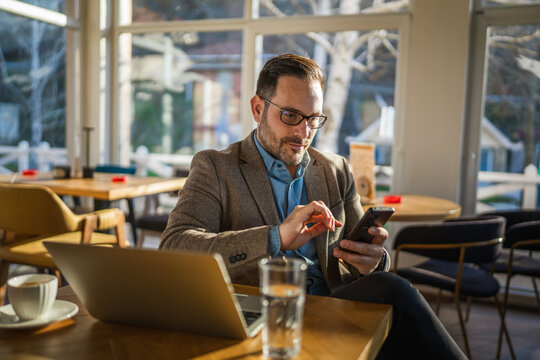 Man connecting with smart phone while working in cafe