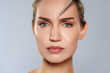 Woman receiving treatment with needle on forehead in a clinic during daylight