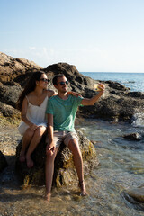 Happy couple taking selfie at a rocky beach