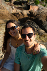 Happy couple enjoying travel selfie on sunny beach
