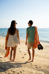 Couple walking barefoot on sandy beach enjoying vacation