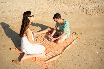 Couple playing card game on beach towel during vacation