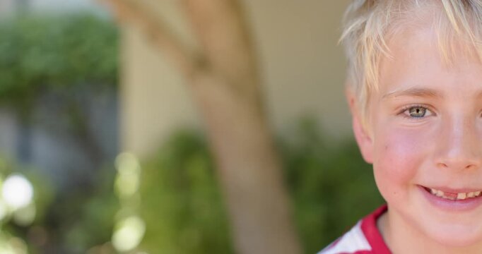 Male child smiling at camera in yard, revealing gap in red-and-white striped shirt, copy space
