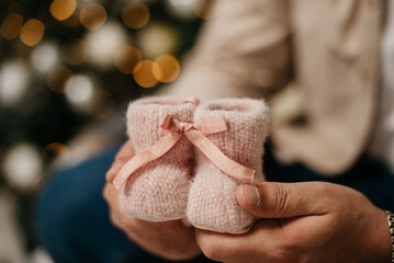 Children's shoes woven from pink threads are held in their hands