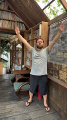 Man with Raised Arms in Expressive Pose within Rustic Library