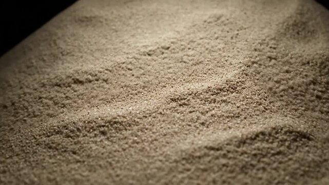 Abstract conical shape formed by fine sand, illuminated against a dark background.