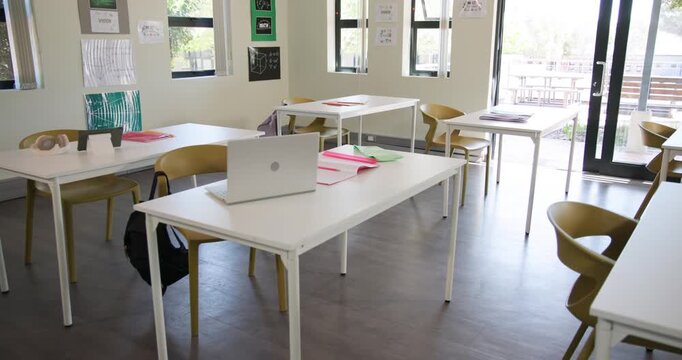 Camera is moving forward drawing silver laptop and pink notebook into view to highlight study area