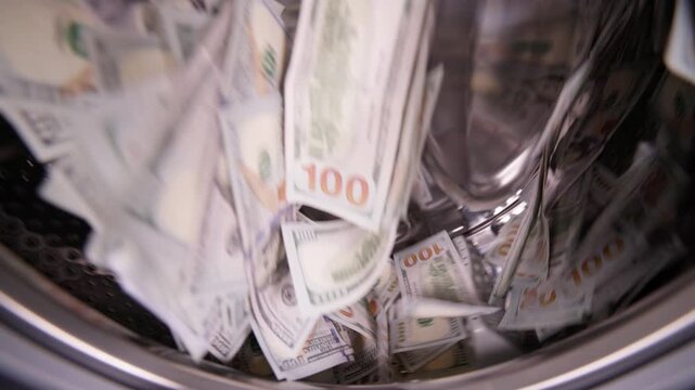 US dollar banknotes spinning inside washing machine in slow motion for money laundering and fraud concept.