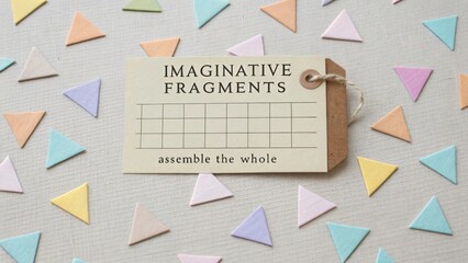 A Labeled Tag With 'Imaginative Fragments' Text Surrounded by Scattered Pastel Paper Triangles
