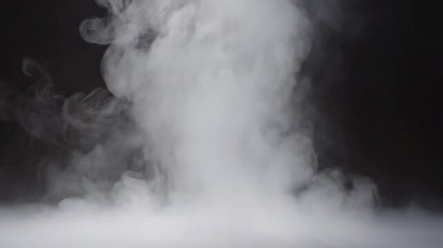 Smoke rises rapidly in a dark room with fog on the floor and walls.