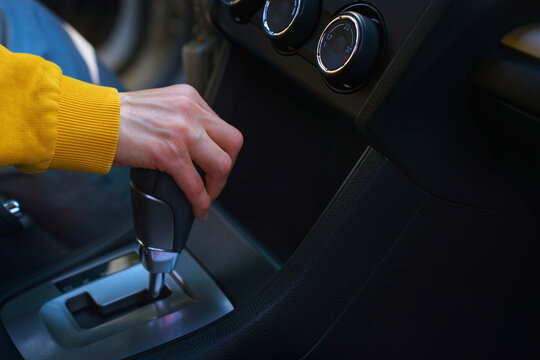 Hand of driver shifting gear in car interior close up