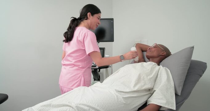 Pink-scrub tech scanning African-American woman neck for exam with probe gel in clinic, copy space