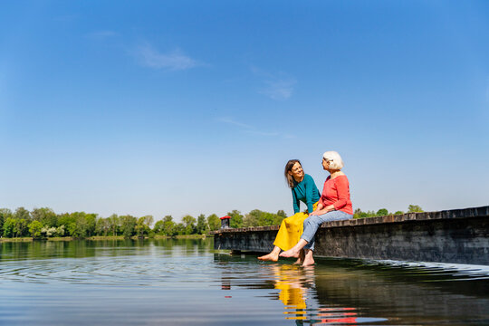 Mother and daughter enjoying leisure time on a jetty by the lake