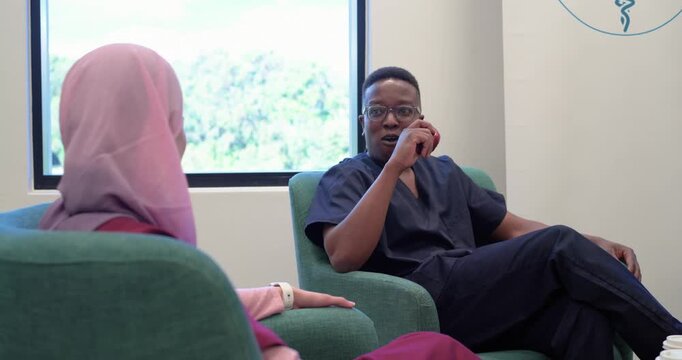 Diverse staff talking in lounge, while colleague speaking male biting apple, then sharing coffee
