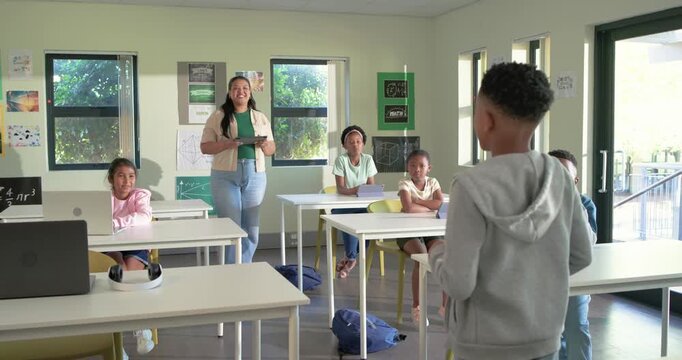 African American boy presenting in class right with teacher with tablet encouraging, copy space