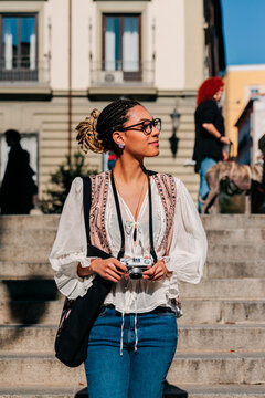 Tourist holding camera on steps outdoors in Madrid on a sunny day
