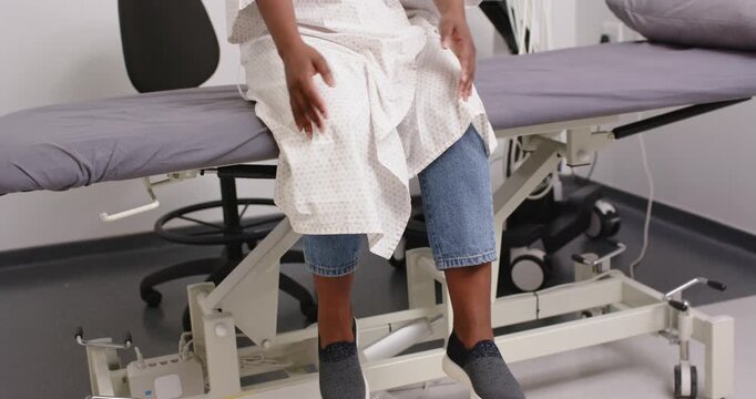 After sitting on table edge patient is shifting hands smoothing gown and settling hands for comfort
